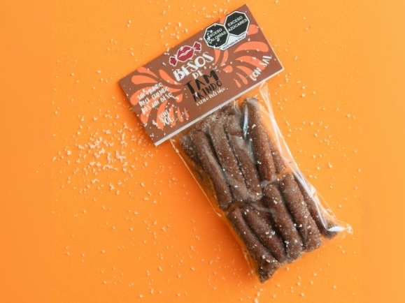 Bolsa de Besos de Tamarindo con sal estilo pellizco sobre fondo naranja